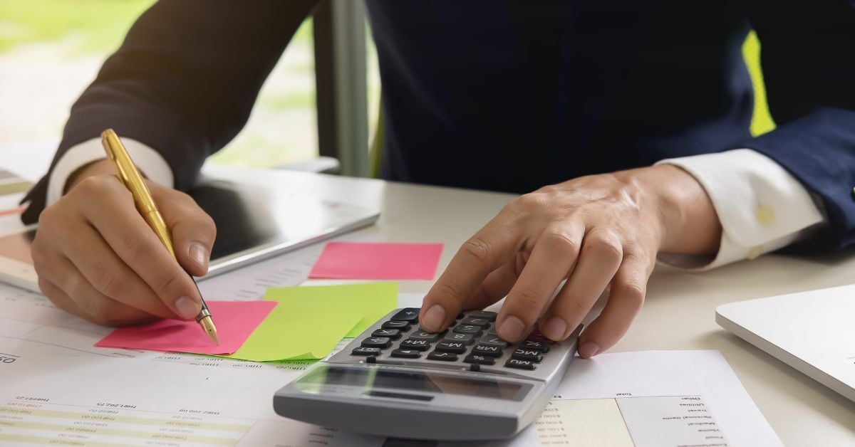 Businessperson calculating finances with notes and documents.